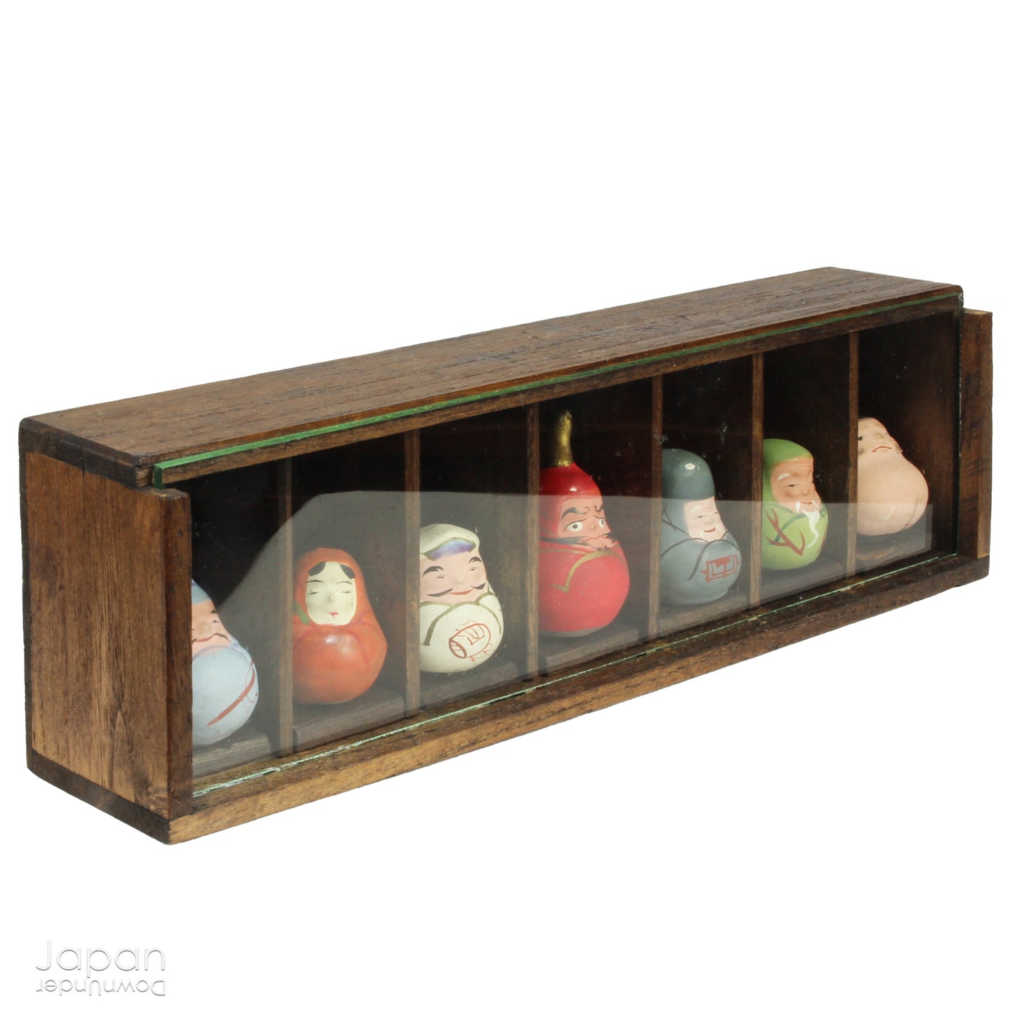 Invite good fortune and timeless tradition into your home with this quaint set of miniature antique Daruma charms. Housed in a charming wooden and glass display box, this unique collection adds an elegant and meaningful touch to your decor, perfect for any space seeking a blend of tradition, luck, and positive energy.

Crafted in the 1920s, this set features hand-painted clay Daruma figures representing the Seven Lucky Gods of Japan, each with its own powerful symbolism.