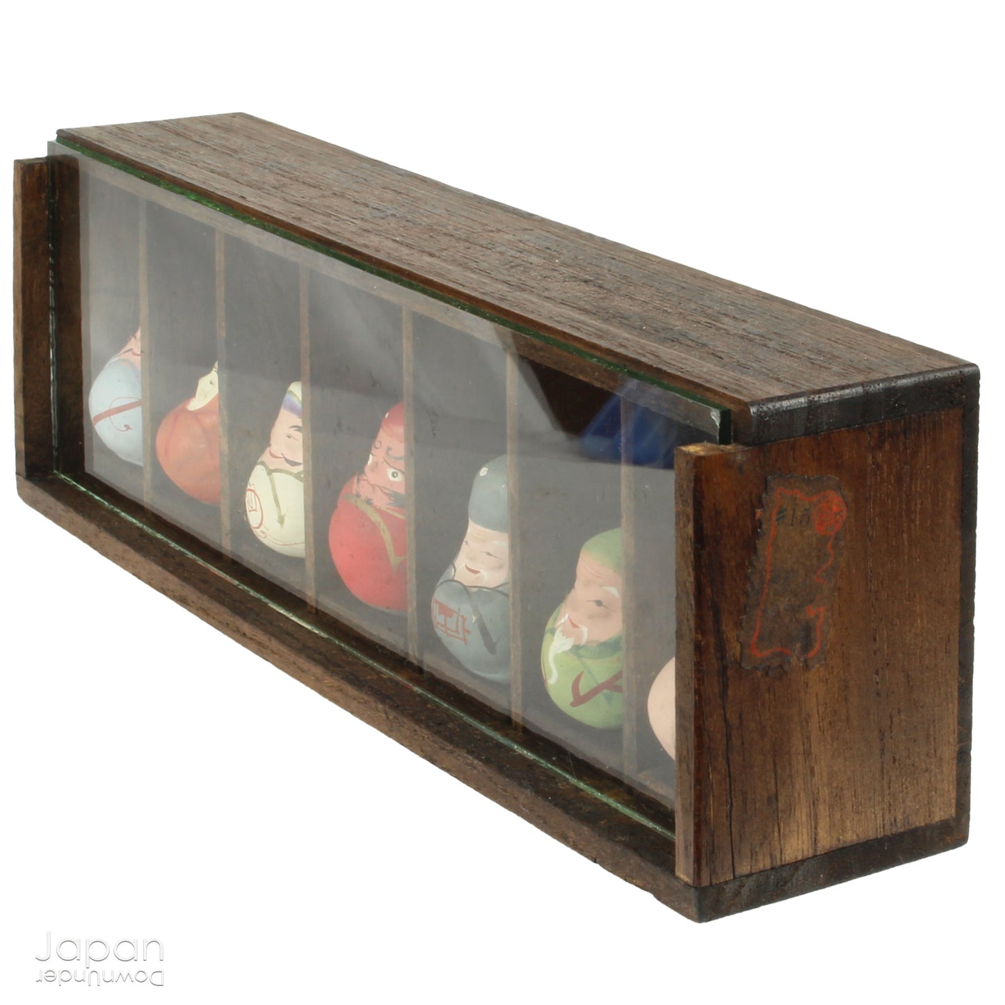 Invite good fortune and timeless tradition into your home with this quaint set of miniature antique Daruma charms. Housed in a charming wooden and glass display box, this unique collection adds an elegant and meaningful touch to your decor, perfect for any space seeking a blend of tradition, luck, and positive energy.

Crafted in the 1920s, this set features hand-painted clay Daruma figures representing the Seven Lucky Gods of Japan, each with its own powerful symbolism.