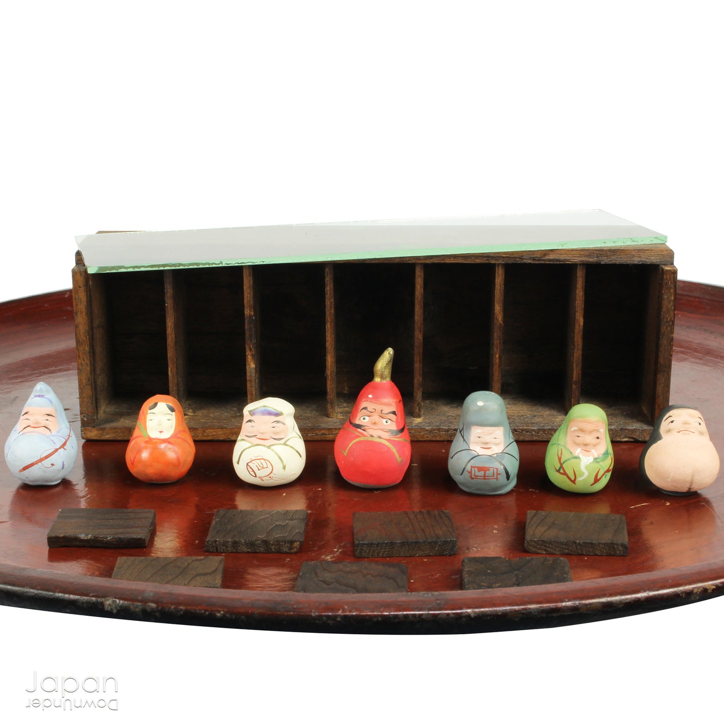 Invite good fortune and timeless tradition into your home with this quaint set of miniature antique Daruma charms. Housed in a charming wooden and glass display box, this unique collection adds an elegant and meaningful touch to your decor, perfect for any space seeking a blend of tradition, luck, and positive energy.

Crafted in the 1920s, this set features hand-painted clay Daruma figures representing the Seven Lucky Gods of Japan, each with its own powerful symbolism.